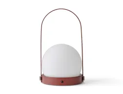 Front view of a burned red Carrie Table Lamp with a white globe shade and tall curved carry handle