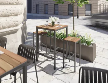 Kyenne High Bar Table with brown slats and charcoal frame, paired with stools beside a restaurant planter