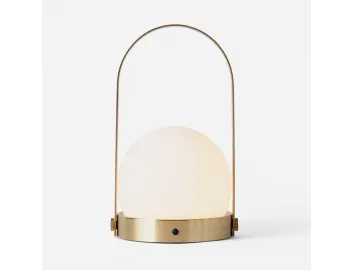 Brass Carrie Table Lamp with a glowing white globe, round gold base and tall arched handle