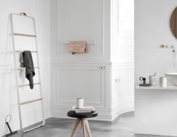 White Norm Towel Ladder holding a dark towel beside a bathroom vanity and a small stool