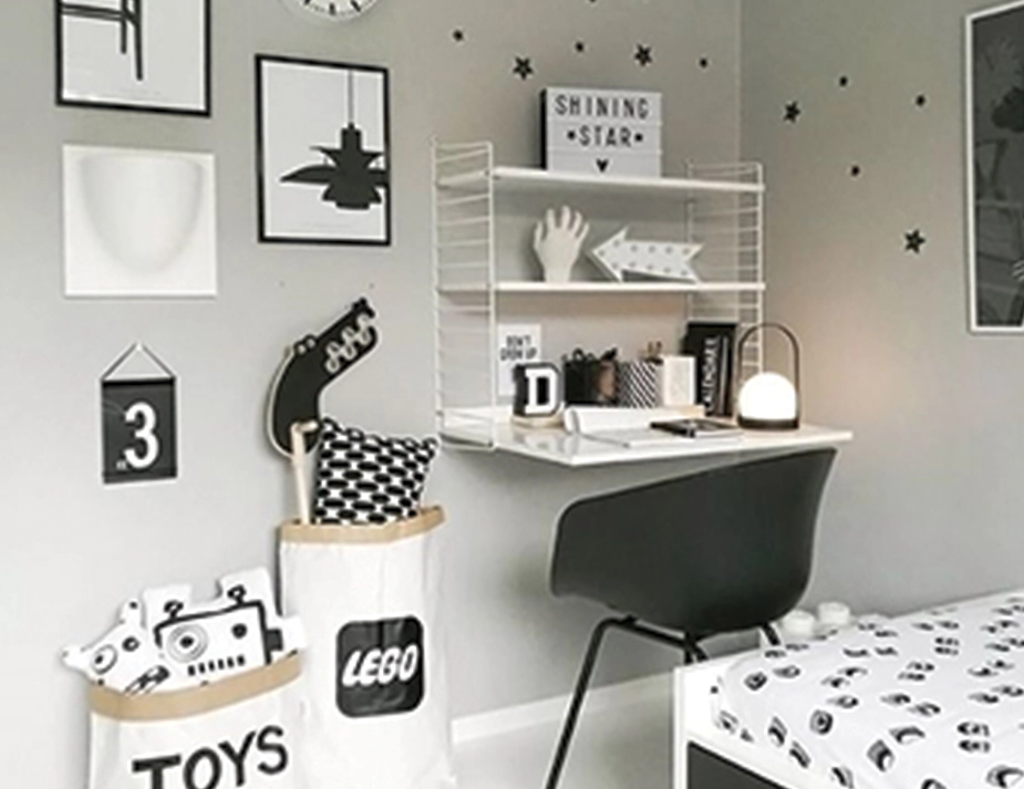 Carrie Table Lamp on a wall-mounted desk beside a bed, toy storage and a black chair in a child’s bedroom